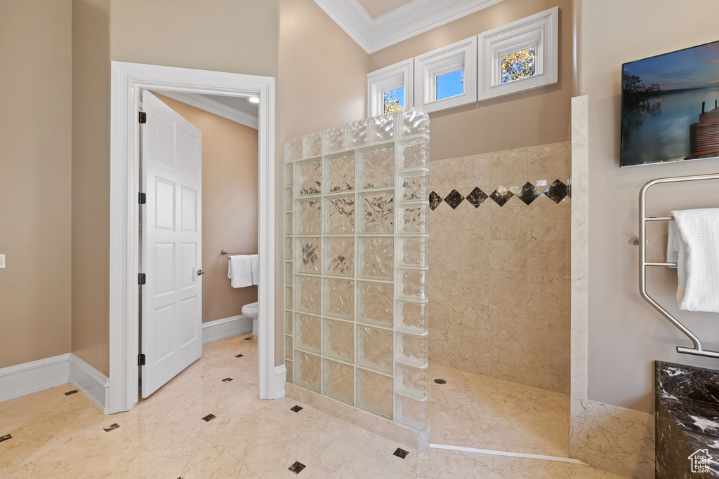 Bathroom featuring crown molding, toilet, and tiled shower