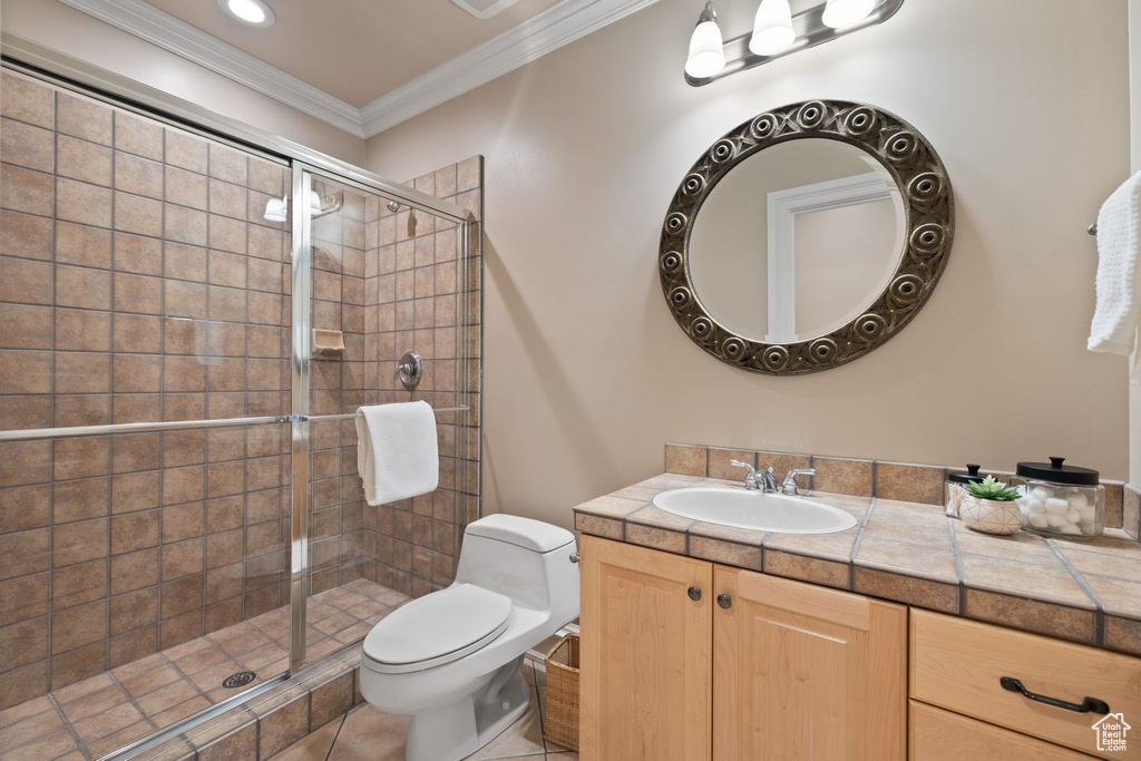 Bathroom featuring crown molding, vanity, tile patterned flooring, toilet, and a shower with shower door