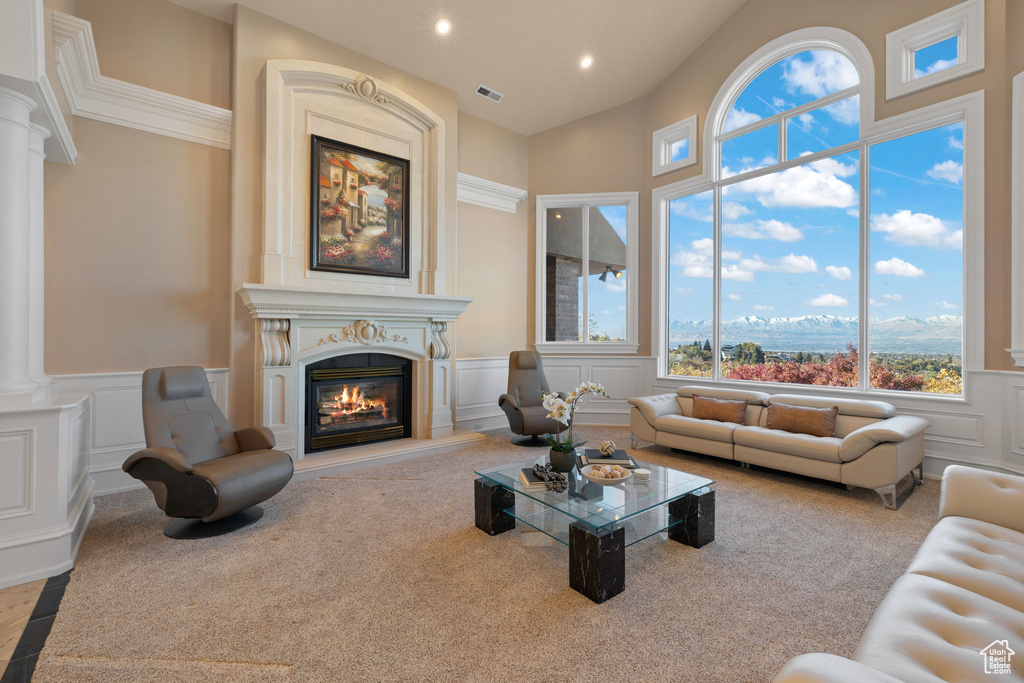 Living room featuring carpet flooring, a high ceiling, and ornate columns