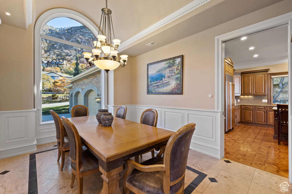 Dining space featuring ornamental molding, light parquet flooring, a healthy amount of sunlight, and an inviting chandelier