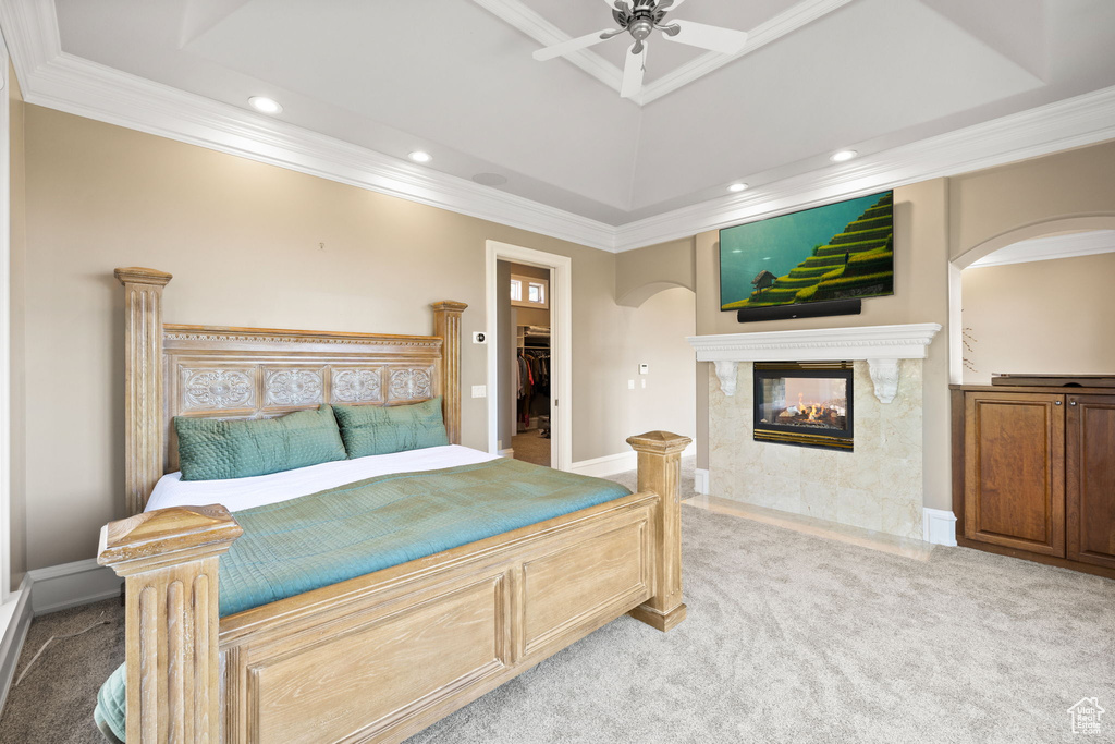 Bedroom featuring light carpet, a multi sided fireplace, ceiling fan, a closet, and a spacious closet