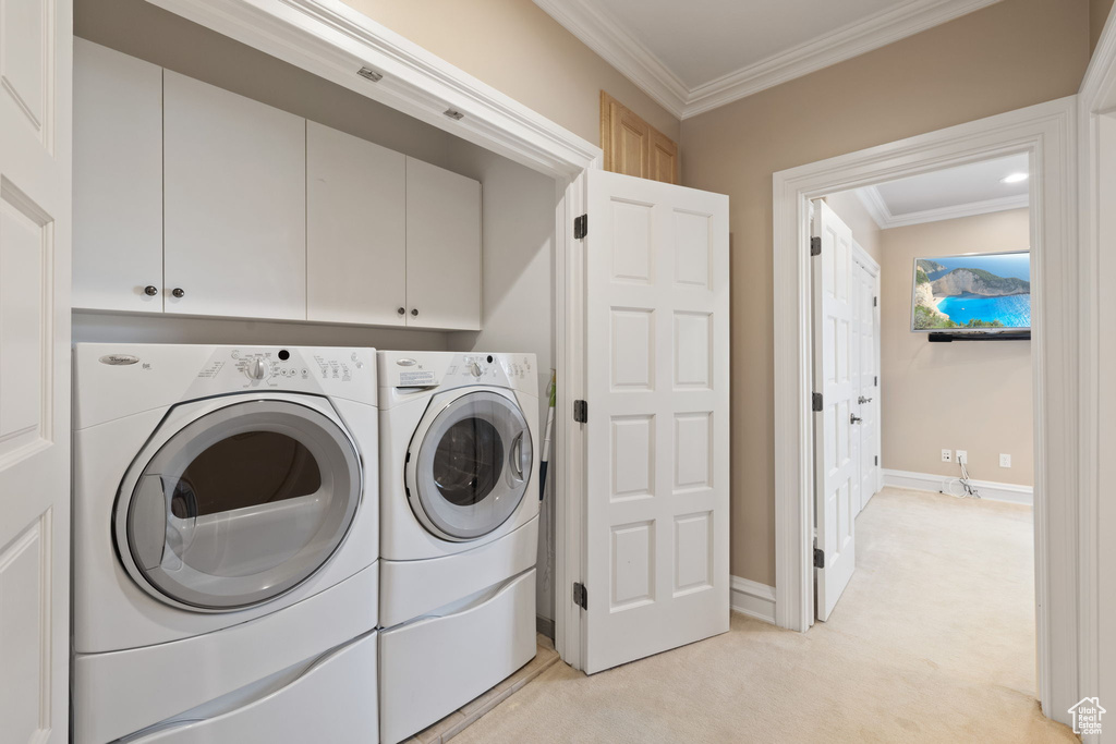 Laundry room with cabinets, light carpet, washing machine and clothes dryer, and crown molding