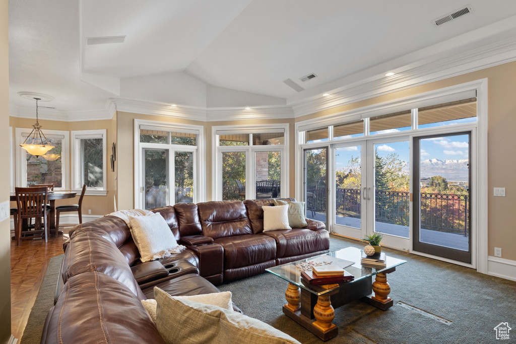 Living room with lofted ceiling, french doors, and ornamental molding