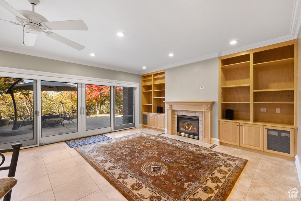 Unfurnished living room with a fireplace, light tile patterned floors, crown molding, and ceiling fan