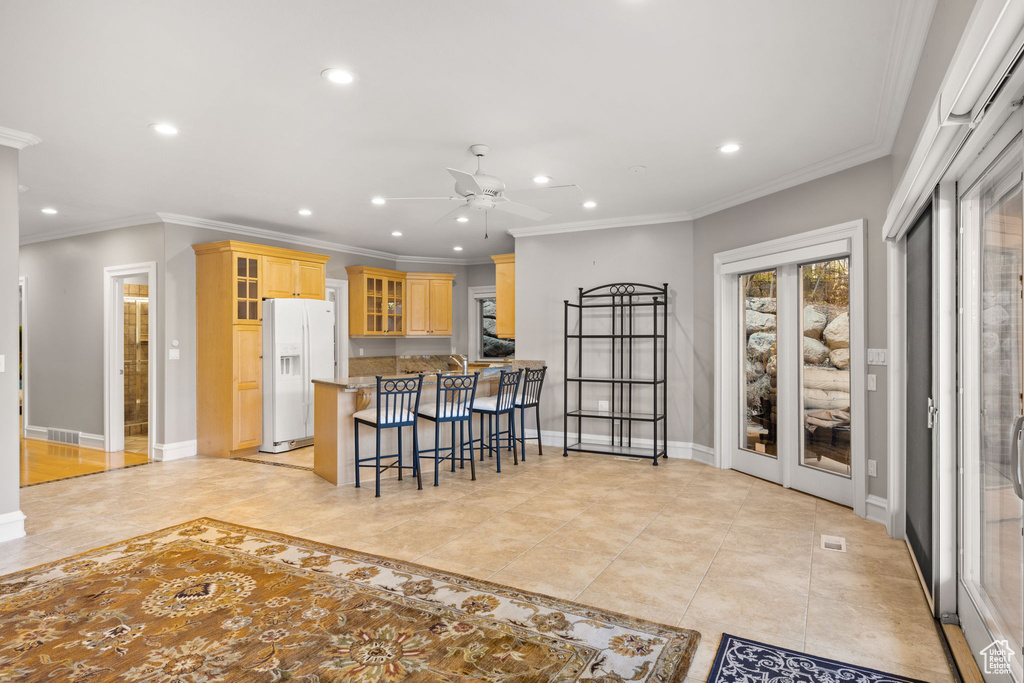 Kitchen featuring ornamental molding, ceiling fan, kitchen peninsula, and white refrigerator with ice dispenser