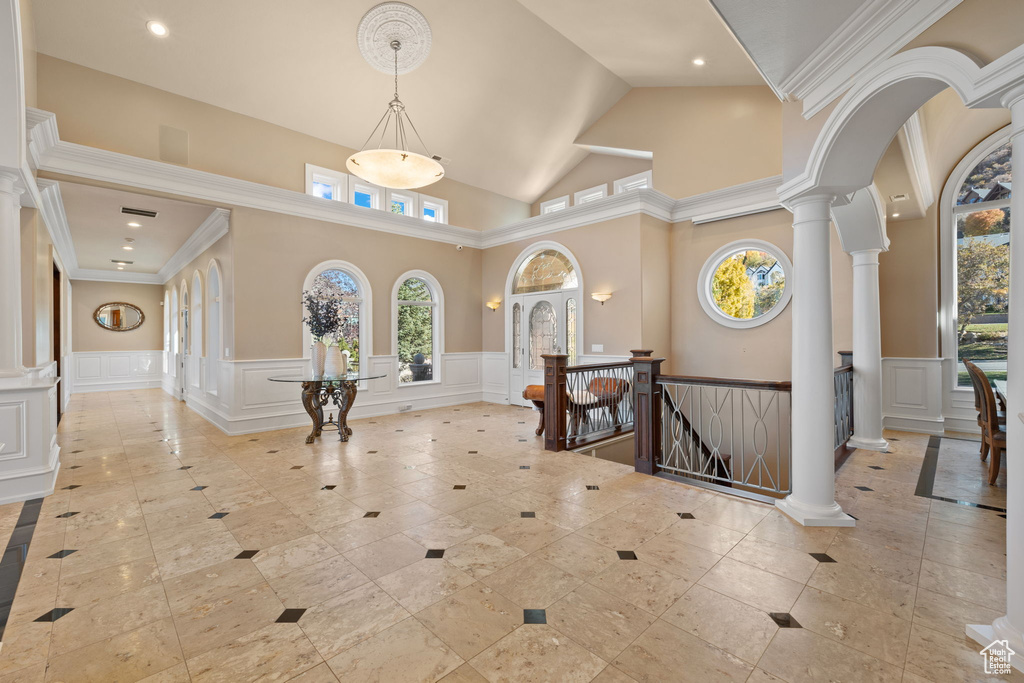 Entrance foyer featuring high vaulted ceiling, decorative columns, and crown molding