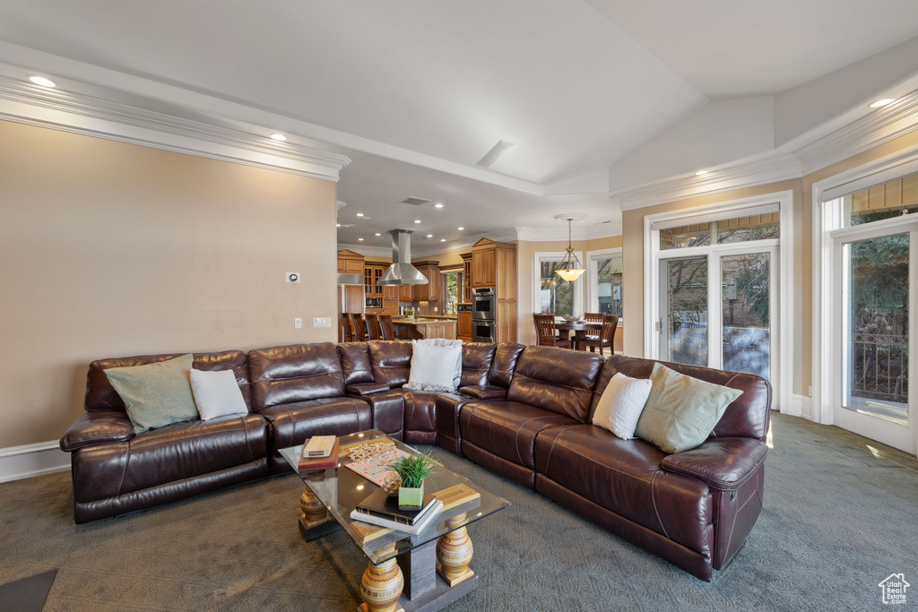 Carpeted living room with lofted ceiling and crown molding