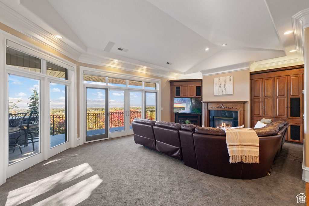 Carpeted living room with ornamental molding, french doors, lofted ceiling, and a high end fireplace