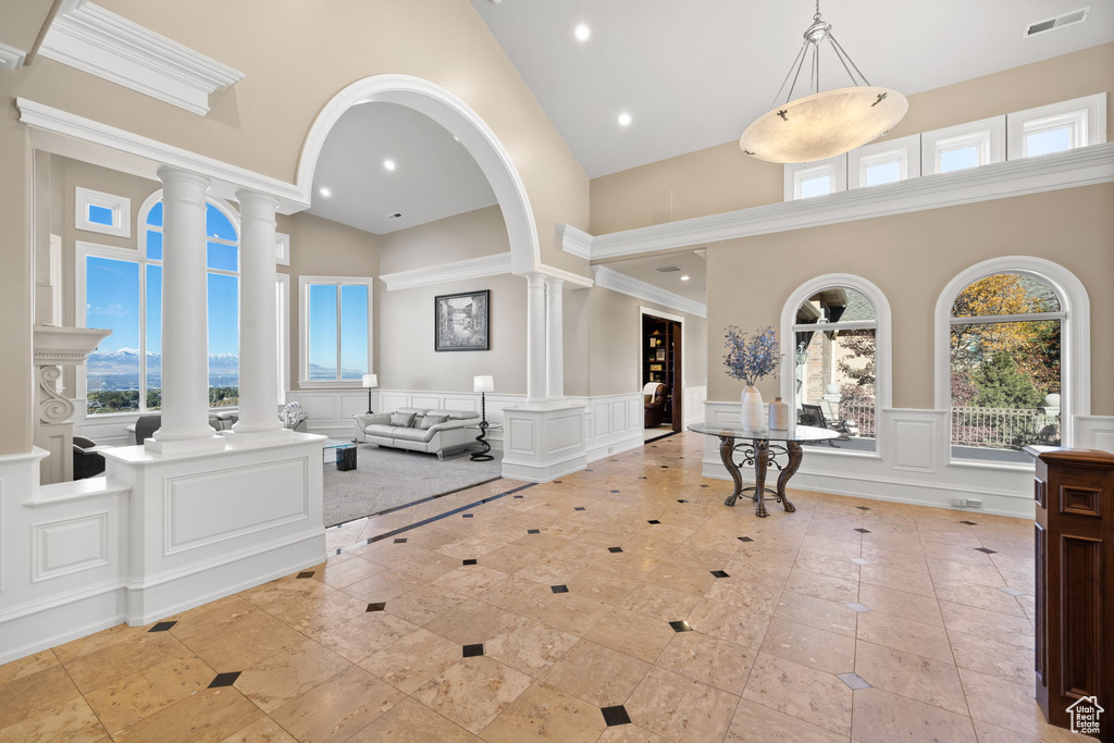 Foyer entrance featuring decorative columns, a healthy amount of sunlight, and a towering ceiling