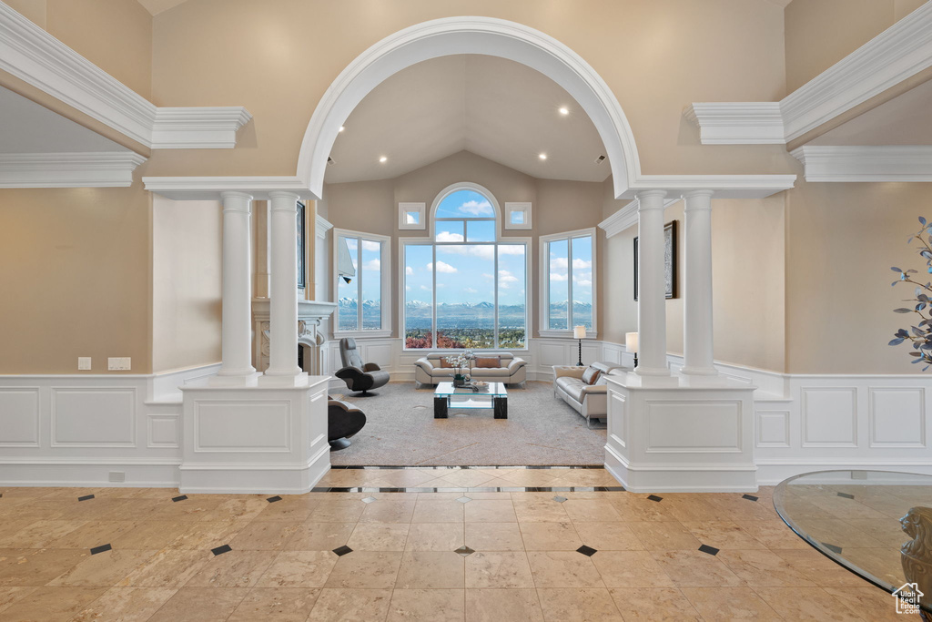 Interior space featuring ornate columns, high vaulted ceiling, and crown molding