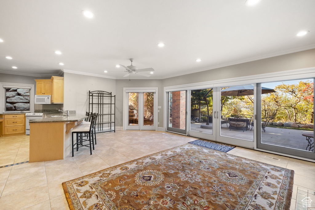 Tiled living room with ornamental molding, french doors, sink, and ceiling fan