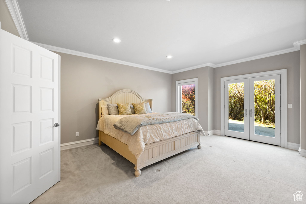 Carpeted bedroom featuring french doors, crown molding, and access to exterior