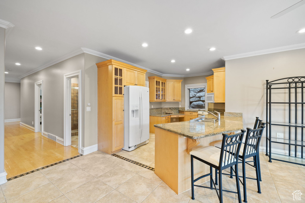 Kitchen featuring ornamental molding, white appliances, light stone countertops, sink, and kitchen peninsula