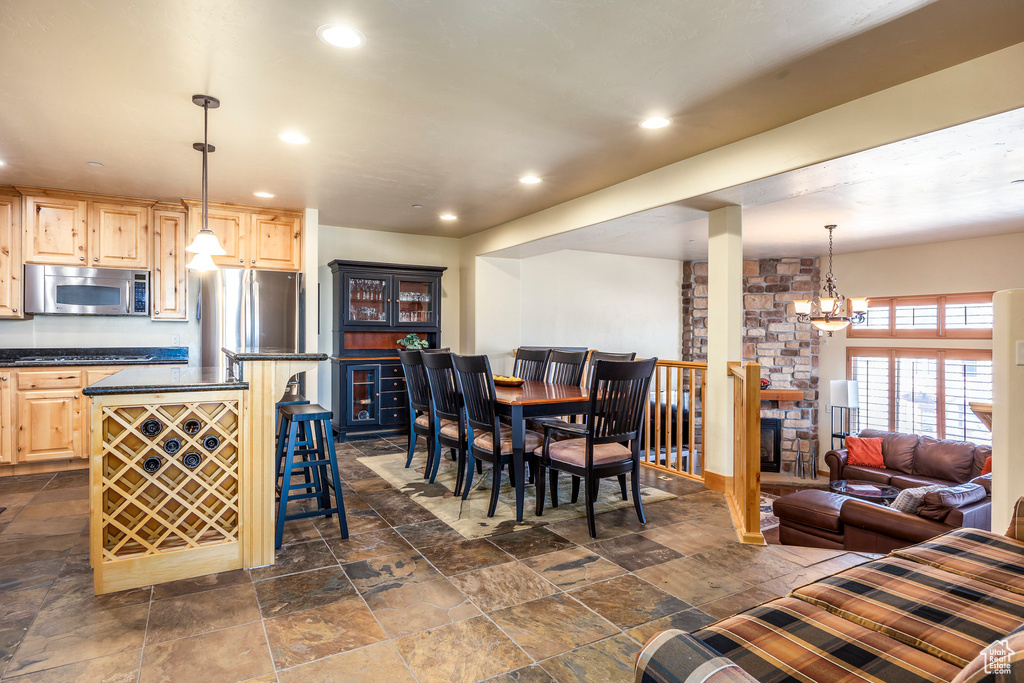 Kitchen with light brown cabinetry, a breakfast bar, decorative light fixtures, and appliances with stainless steel finishes