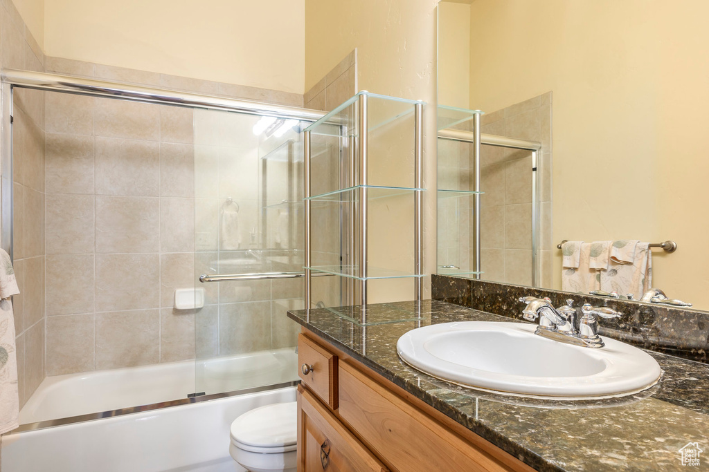 Full bathroom featuring shower / bath combination with glass door, vanity, and toilet