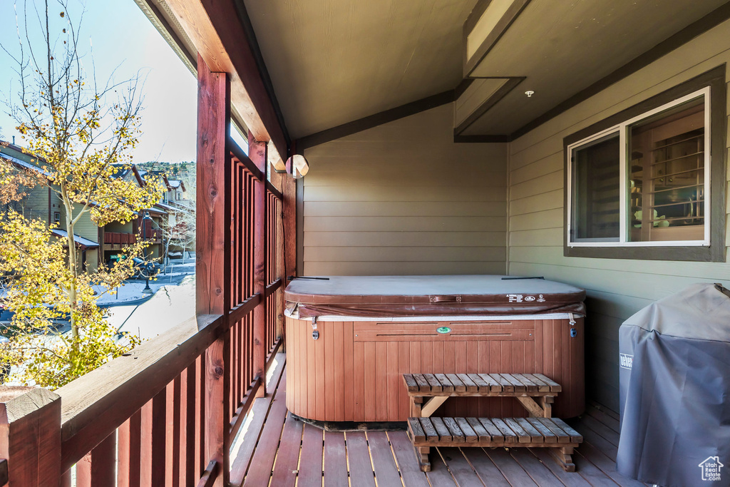 Wooden deck with a hot tub and a grill