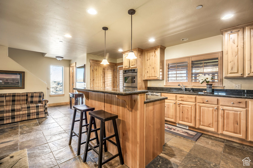 Kitchen featuring a kitchen island, pendant lighting, sink, a breakfast bar area, and oven