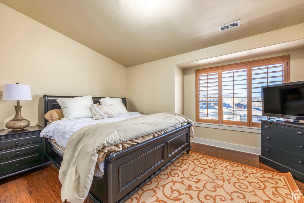 Bedroom with hardwood / wood-style flooring and vaulted ceiling