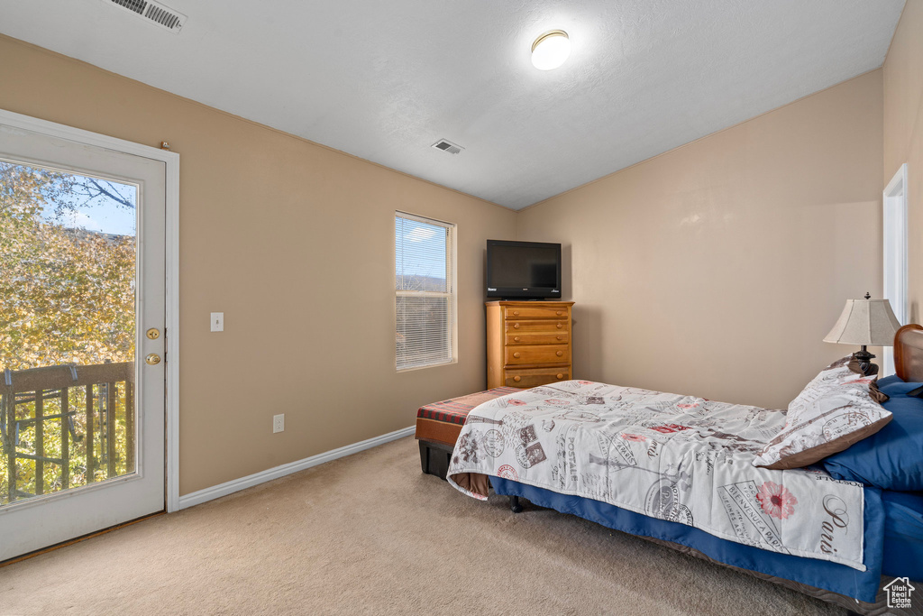 Bedroom featuring access to outside, lofted ceiling, and carpet