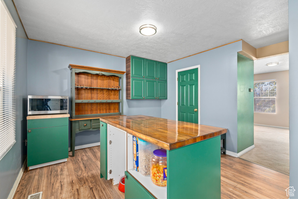 Kitchen featuring wood counters, a textured ceiling, light hardwood / wood-style flooring, and green cabinets