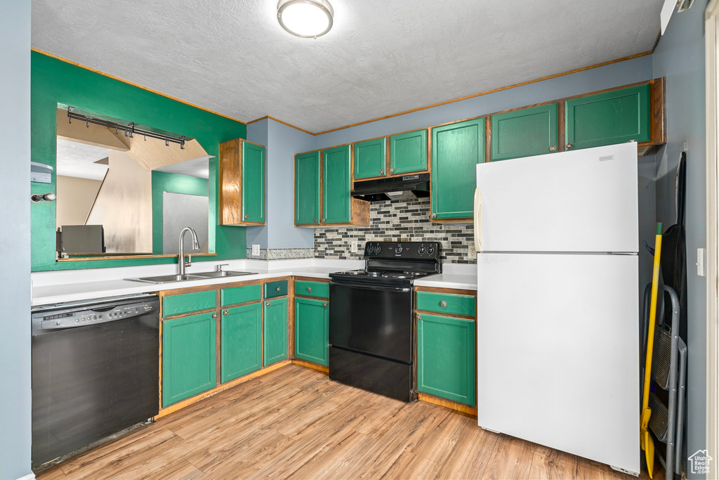 Kitchen featuring light wood-type flooring, black appliances, sink, and tasteful backsplash