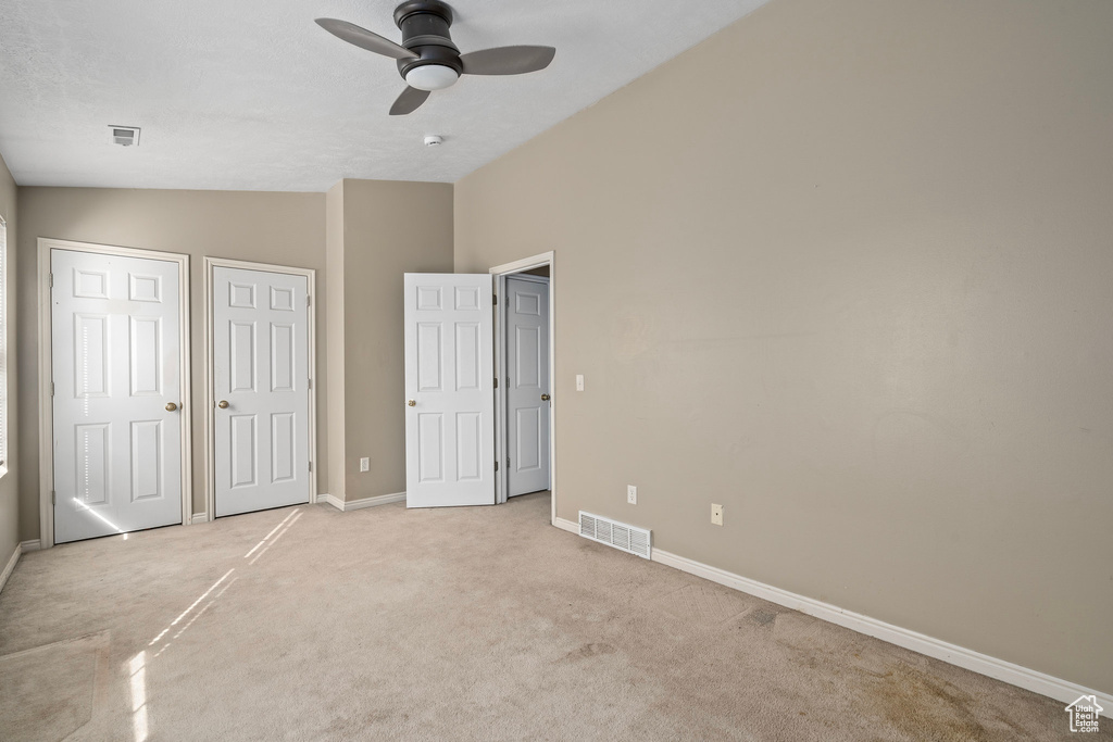 Unfurnished bedroom with vaulted ceiling, light carpet, and ceiling fan