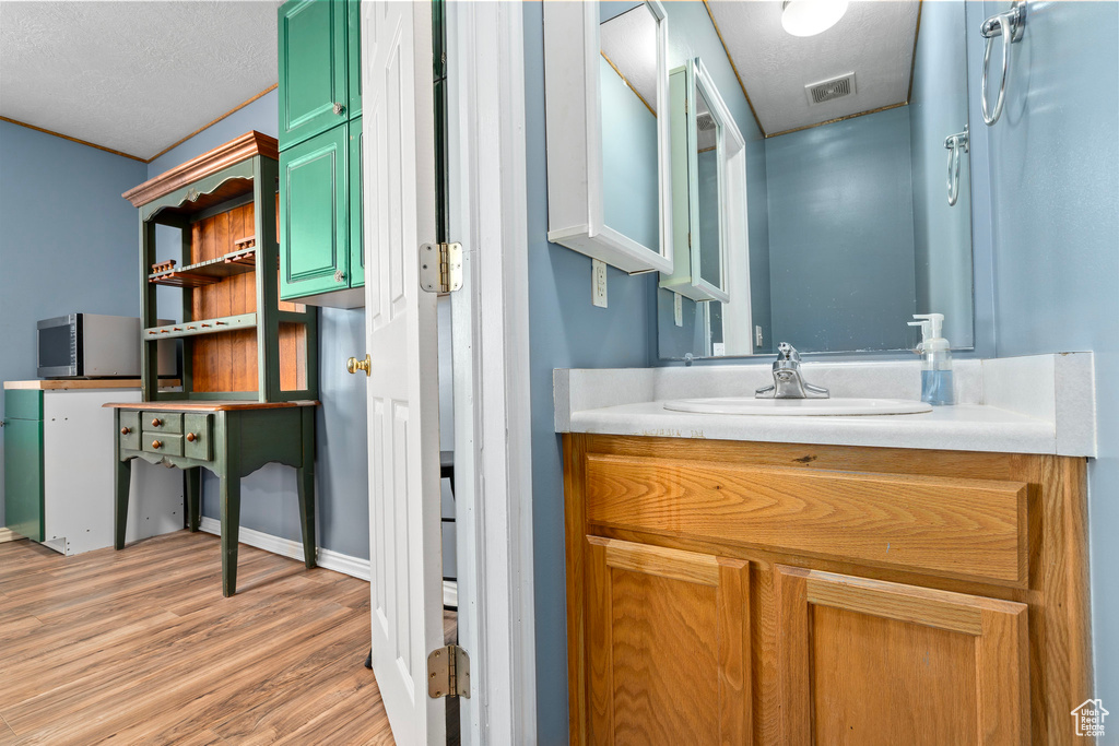 Bathroom with hardwood / wood-style floors, vanity, and a textured ceiling