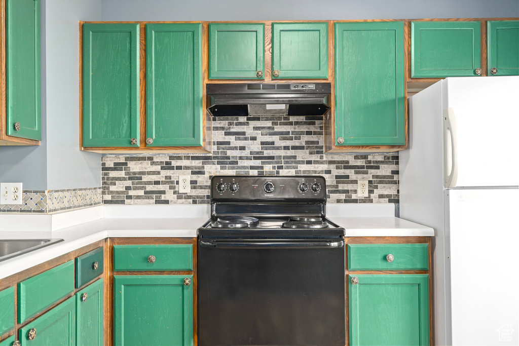 Kitchen with electric stove, white refrigerator, and backsplash