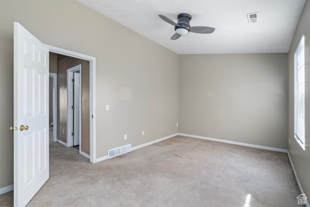 Carpeted empty room featuring ceiling fan