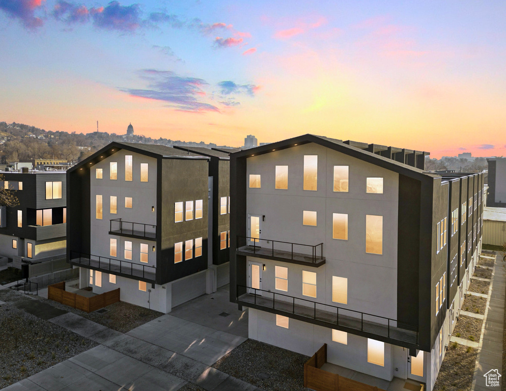 Back of property at dusk featuring a balcony and stucco siding