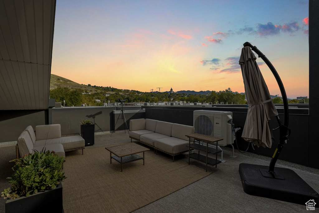 Patio terrace at dusk featuring outdoor lounge area, a mountain view, and ac unit