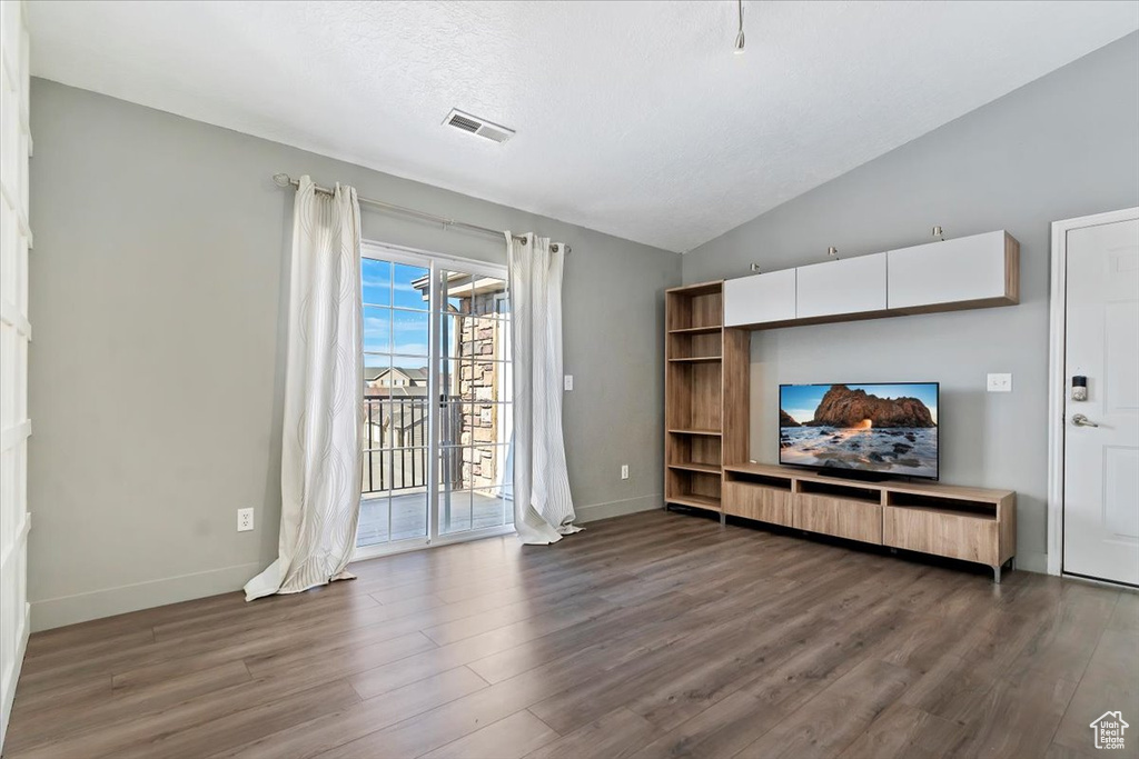 Living area with vaulted ceiling, dark wood-style flooring, visible vents, and baseboards