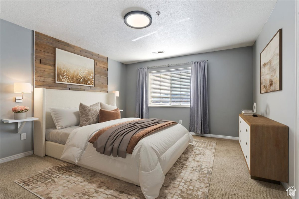Bedroom featuring wood walls, baseboards, a textured ceiling, and light colored carpet