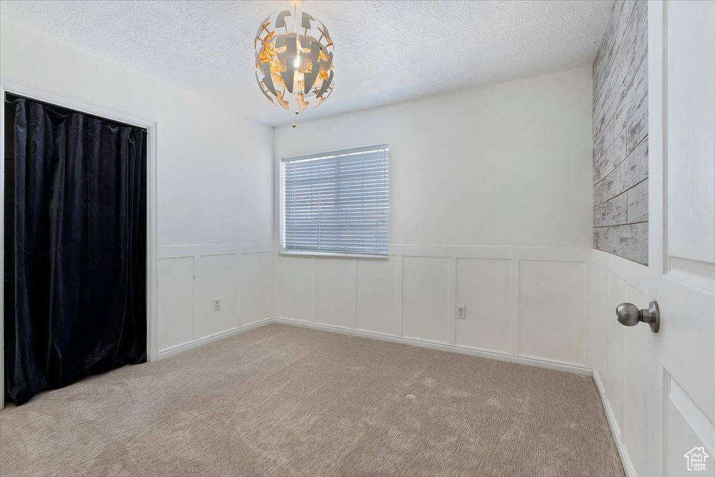 Spare room with wainscoting, a textured ceiling, and light colored carpet