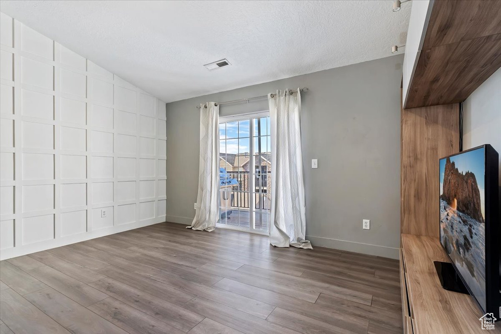 Interior space featuring lofted ceiling, visible vents, a textured ceiling, wood finished floors, and baseboards