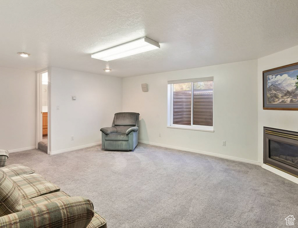 Unfurnished room with baseboards, carpet, a glass covered fireplace, and a textured ceiling