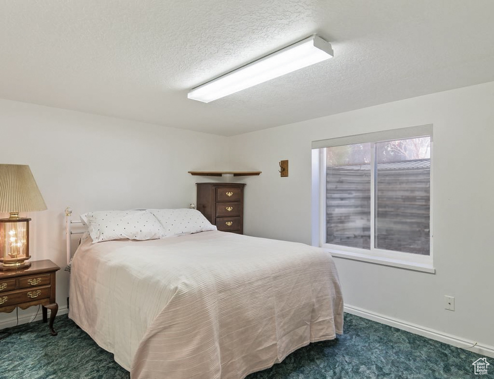 Carpeted bedroom with baseboards and a textured ceiling