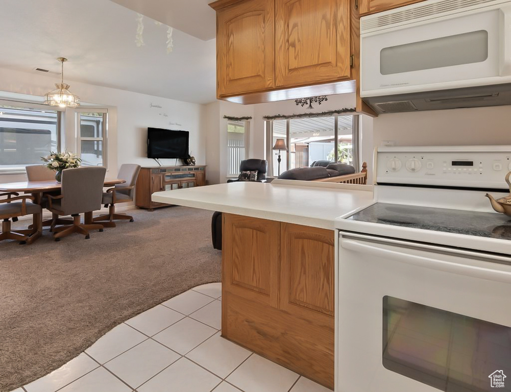 Kitchen featuring light carpet, white appliances, open floor plan, light countertops, and light tile patterned flooring