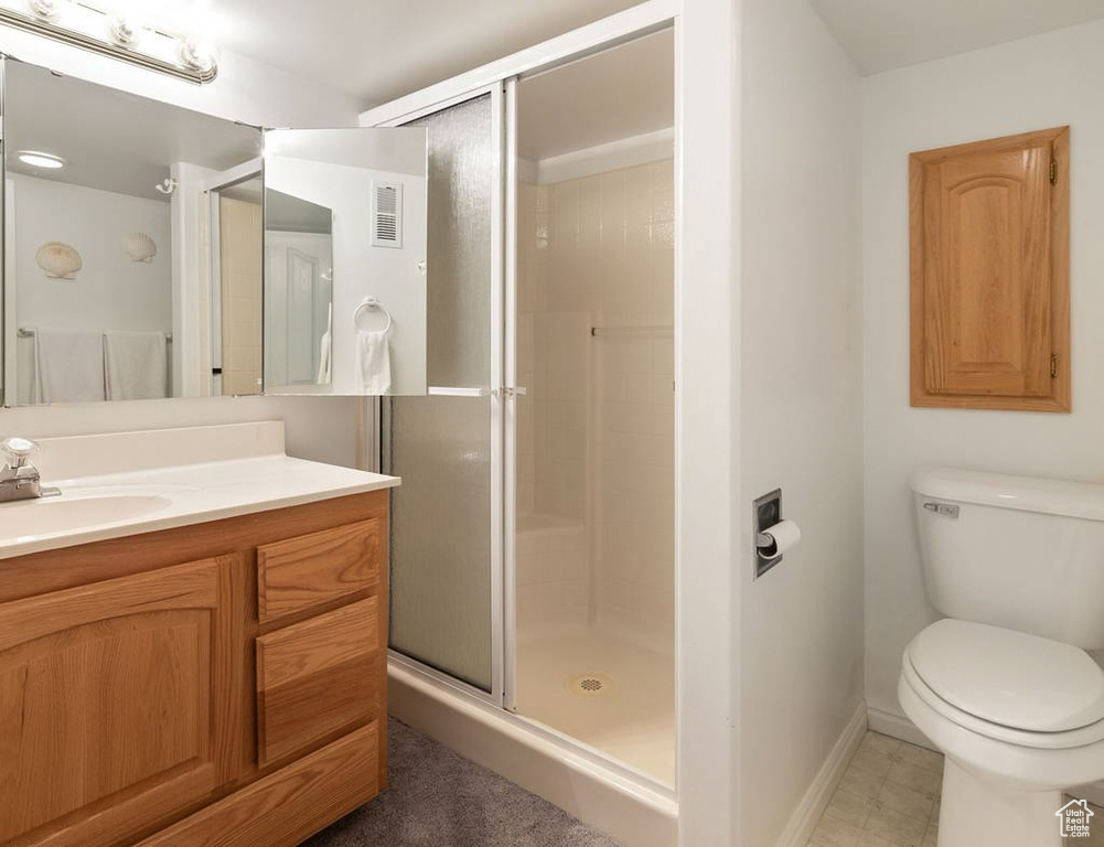 Full bathroom with visible vents, baseboards, toilet, a shower stall, and vanity