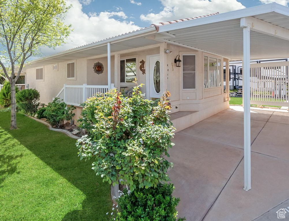 View of front facade with a carport, stucco siding, and a front lawn