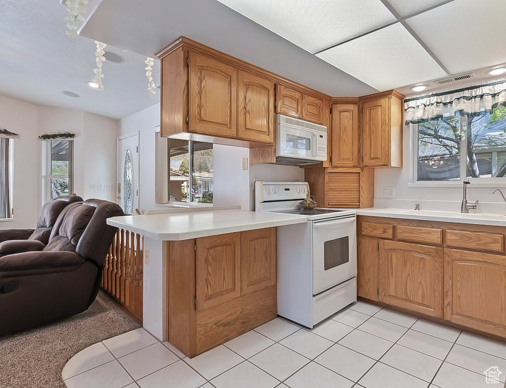 Kitchen with open floor plan, light countertops, a sink, and white appliances