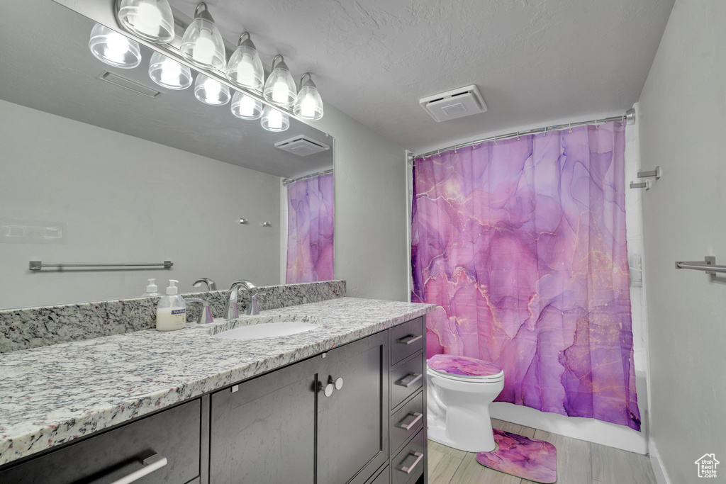 Full bathroom with vanity, a textured ceiling, toilet, and shower / tub combo