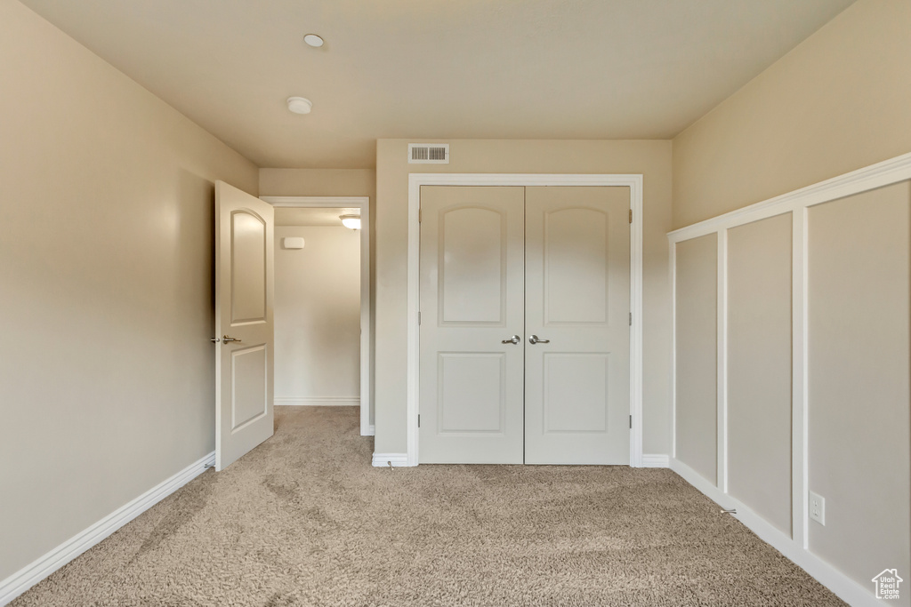 Unfurnished bedroom featuring light carpet and a closet