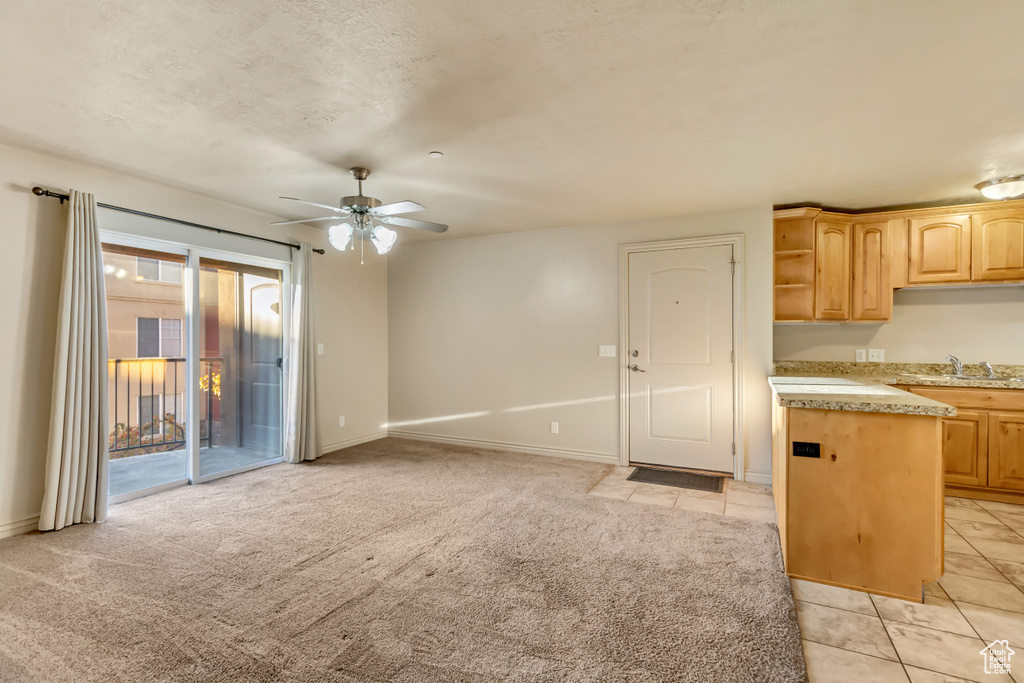 Kitchen featuring light carpet, light brown cabinetry, sink, and ceiling fan