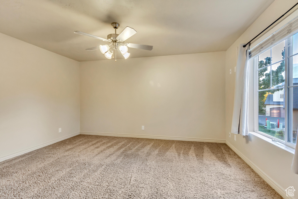 Unfurnished room with a wealth of natural light, carpet flooring, and ceiling fan