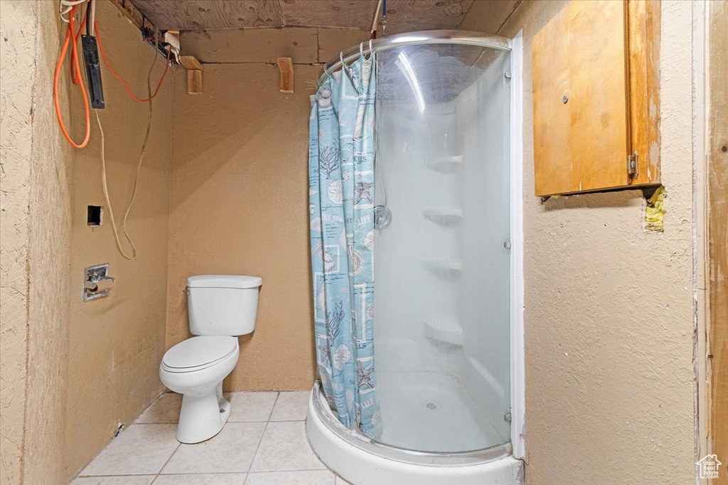 Bathroom featuring walk in shower, tile patterned flooring, and toilet