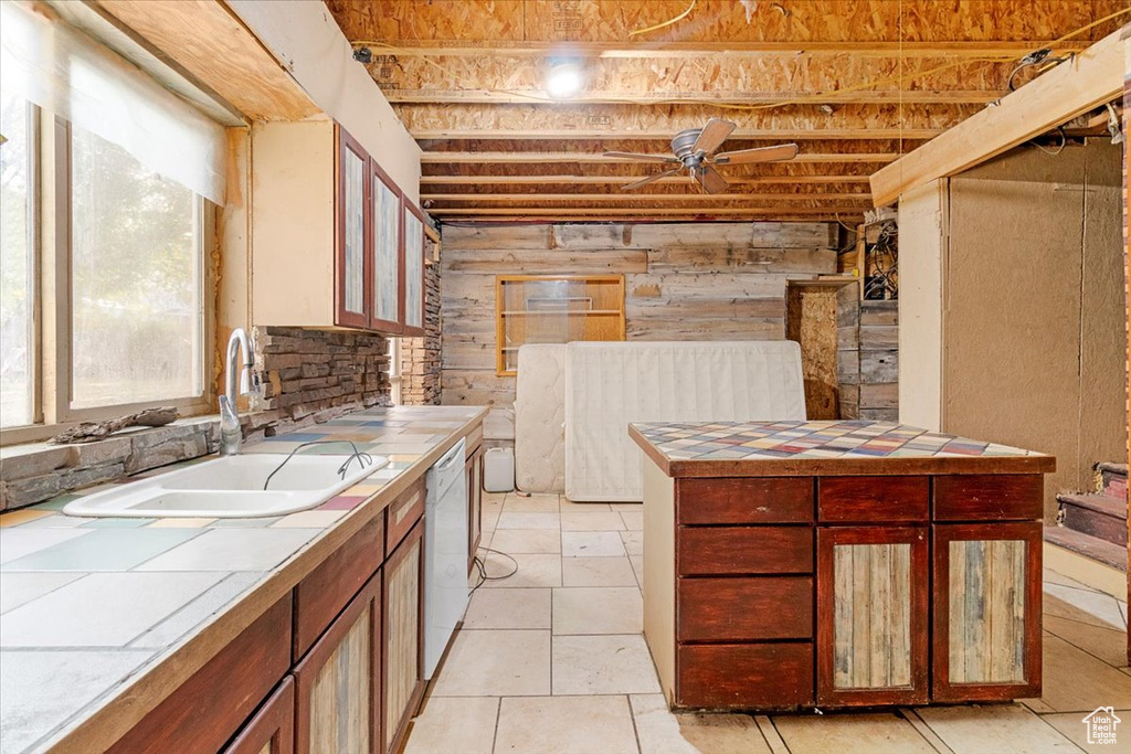 Kitchen featuring tile countertops, sink, ceiling fan, and dishwasher