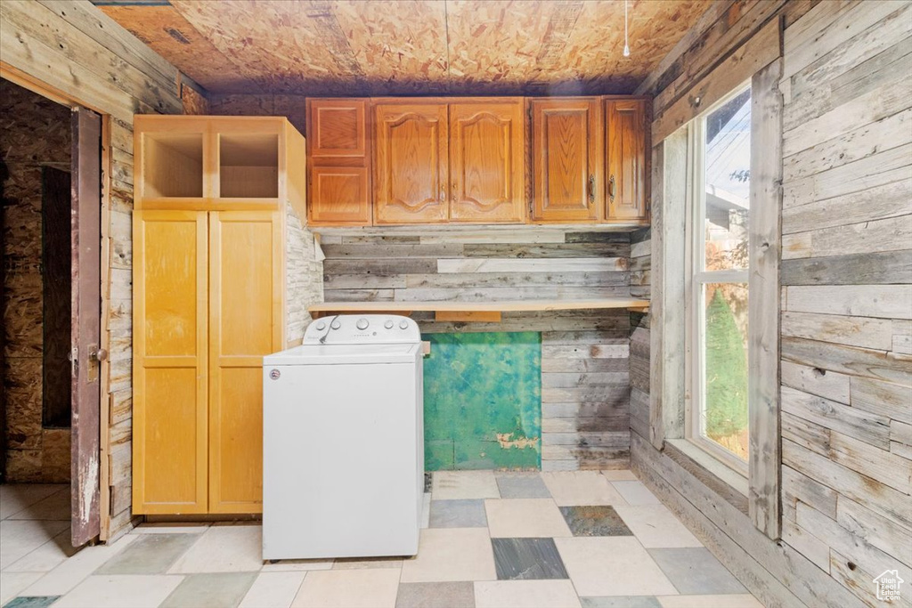 Laundry area featuring plenty of natural light, washer / clothes dryer, cabinets, and wooden walls