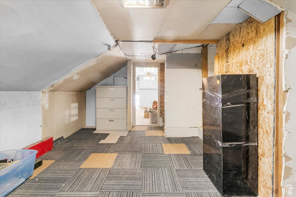 Bonus room featuring vaulted ceiling and dark carpet