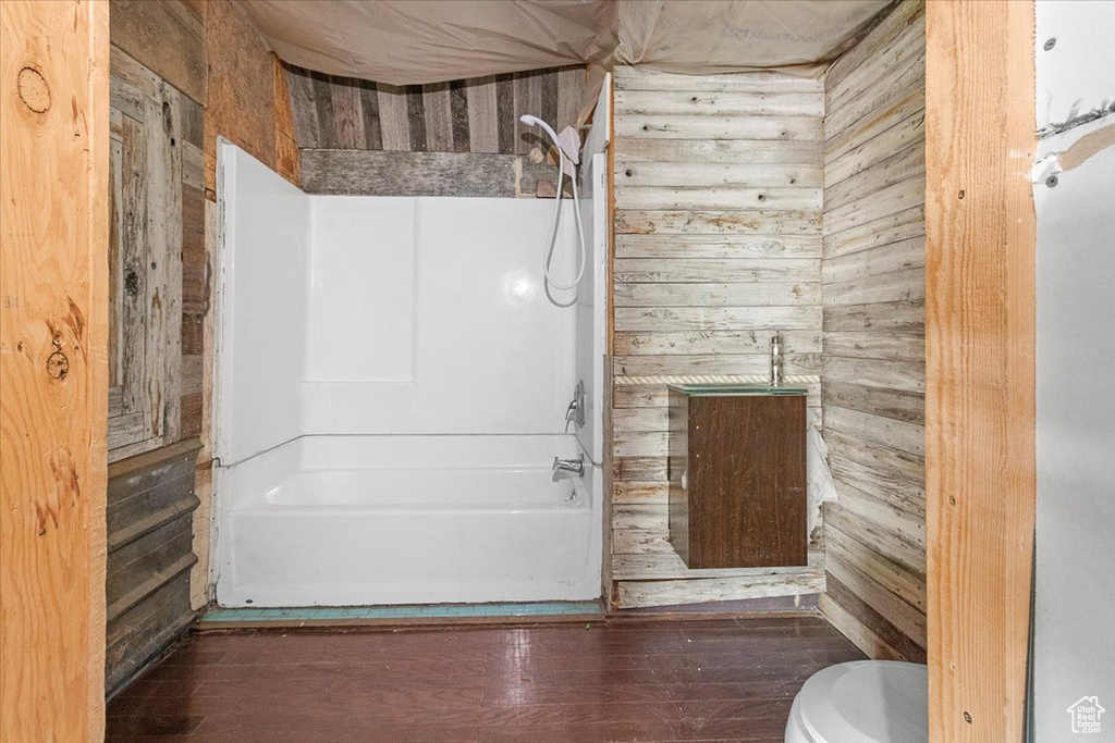 Bathroom with wood walls, hardwood / wood-style flooring, and toilet